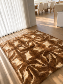 1970s alpaca wool blanket laid on a wood floor beside sheer curtains