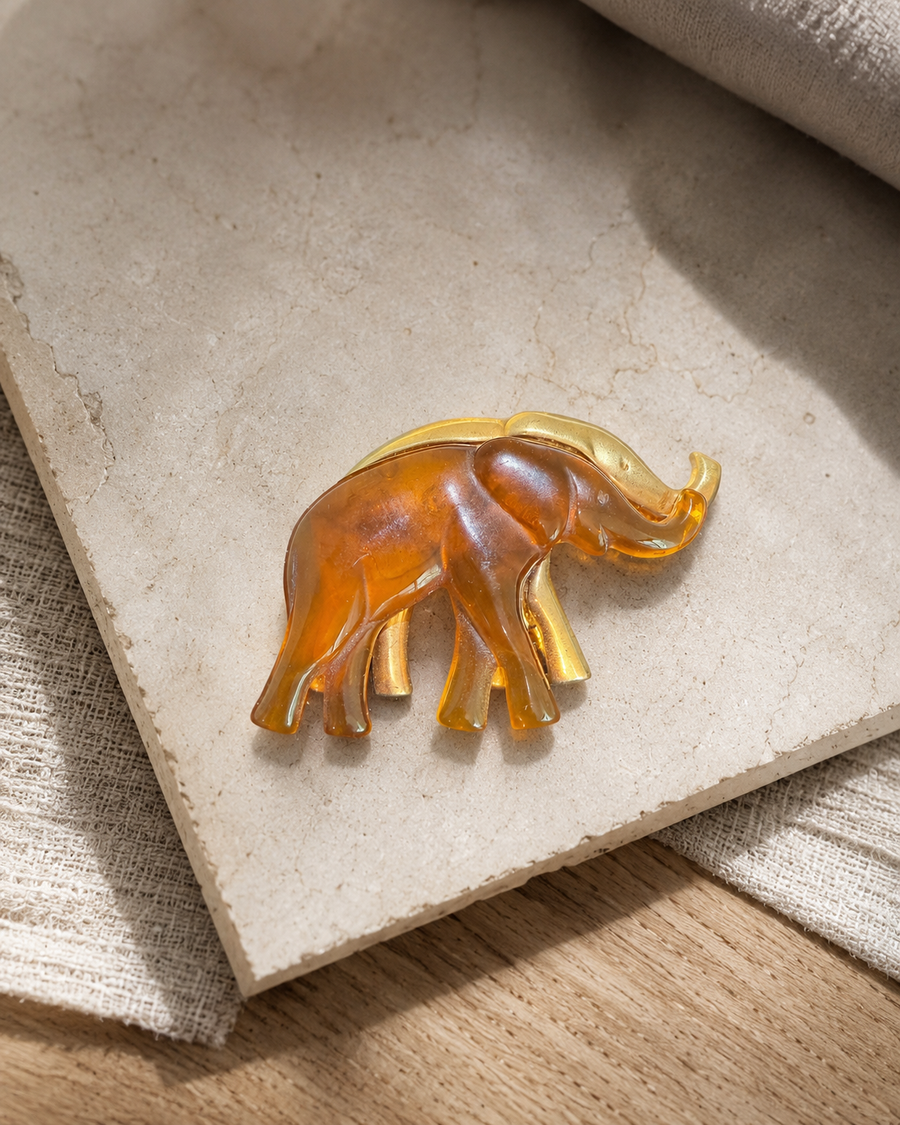 Amber elephant brooch on a pale stone surface