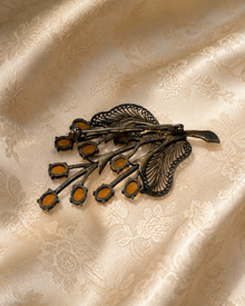Back view of antique floral brooch on cream jacquard fabric