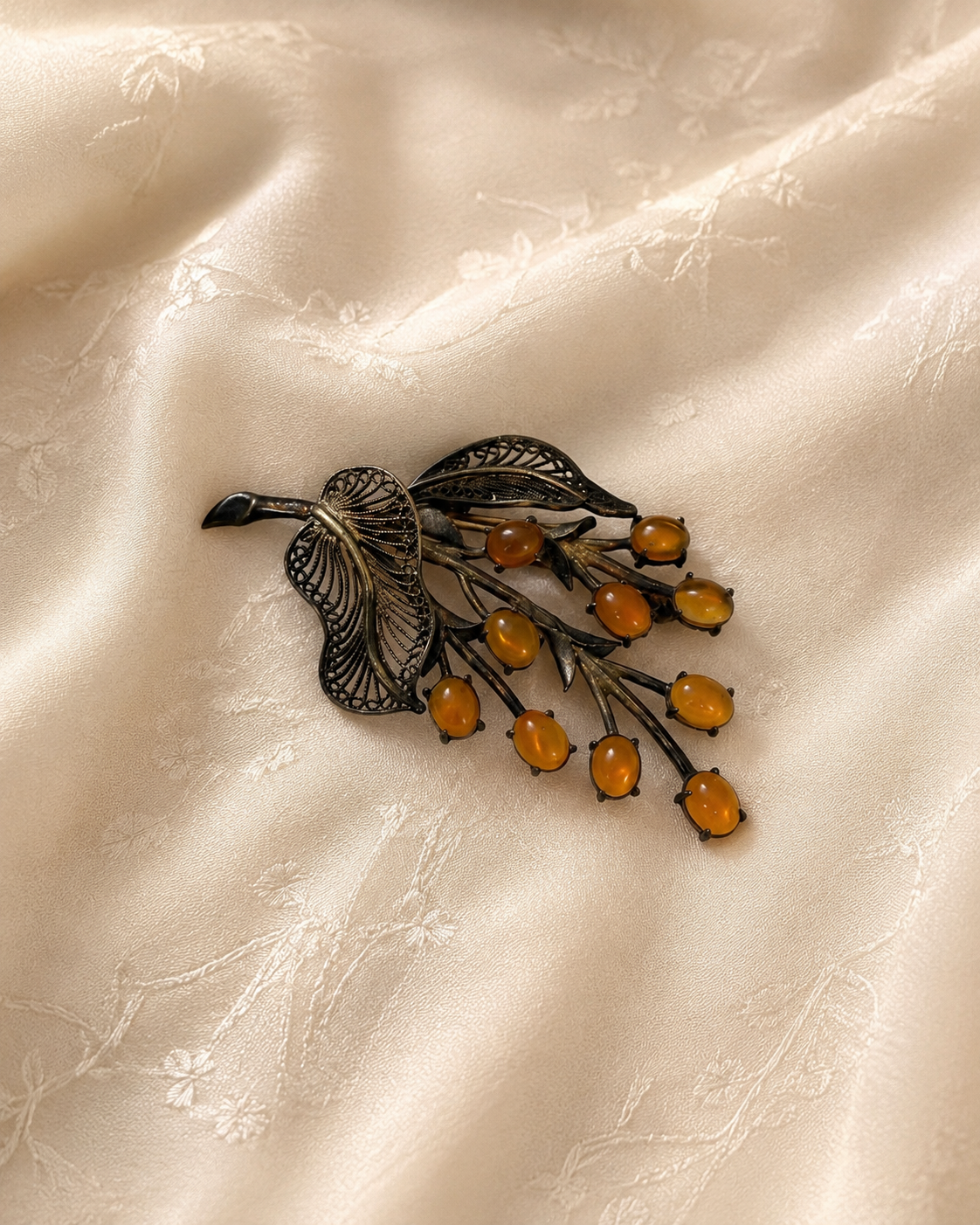 Antique floral brooch with amber-colored cabochons on cream fabric