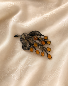 Antique floral brooch with amber-colored cabochons on cream fabric