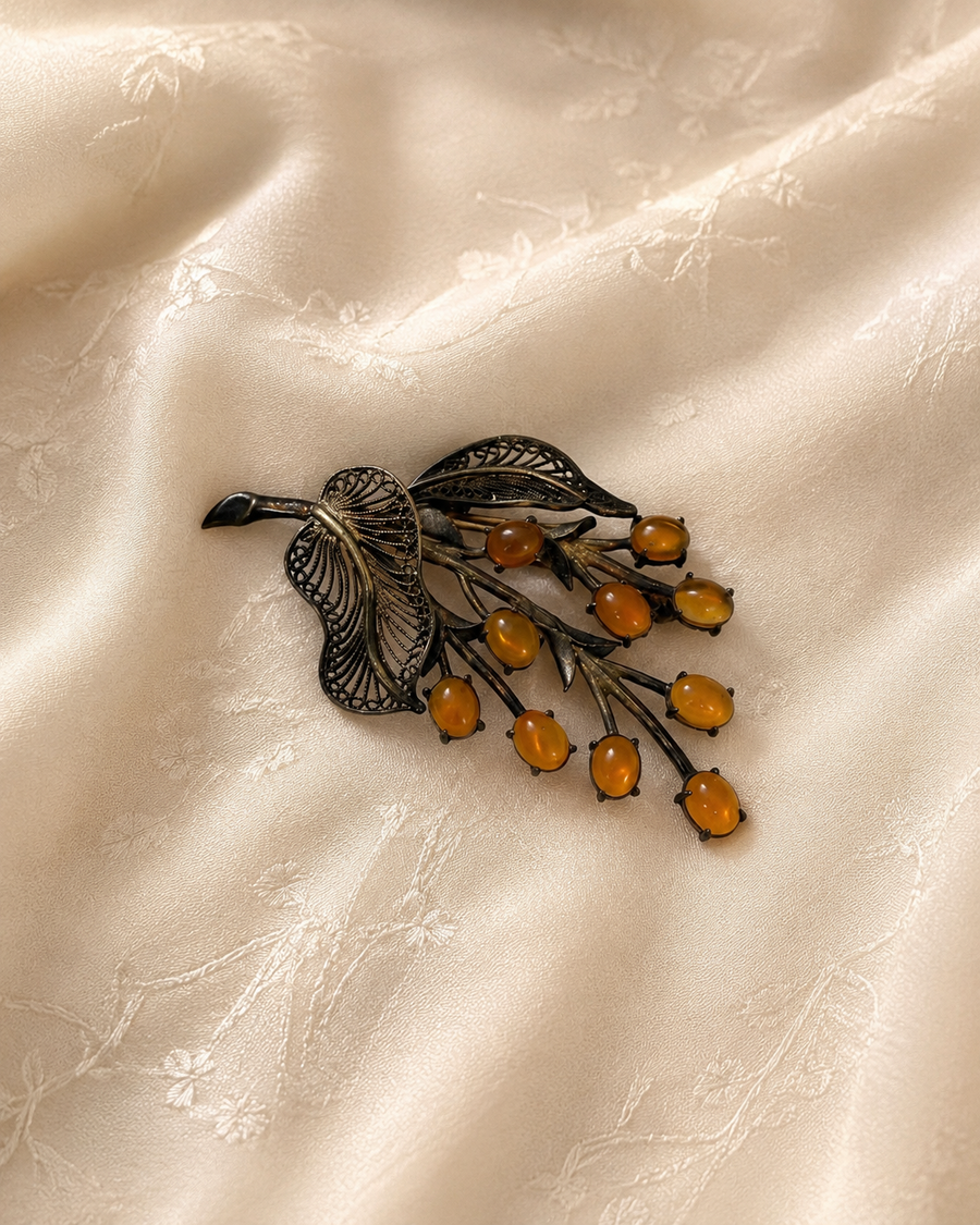 Antique floral brooch with amber-colored cabochons on cream fabric