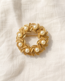 Vintage Avon gold-tone faux pearl wreath brooch on linen