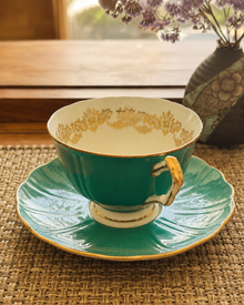 Aynsley turquoise bone china teacup and saucer displayed by a window