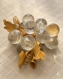 Close detail of crystal-look grape cluster brooch and gold-tone leaves