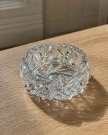 Vintage cut crystal ashtray on wood table with light reflections