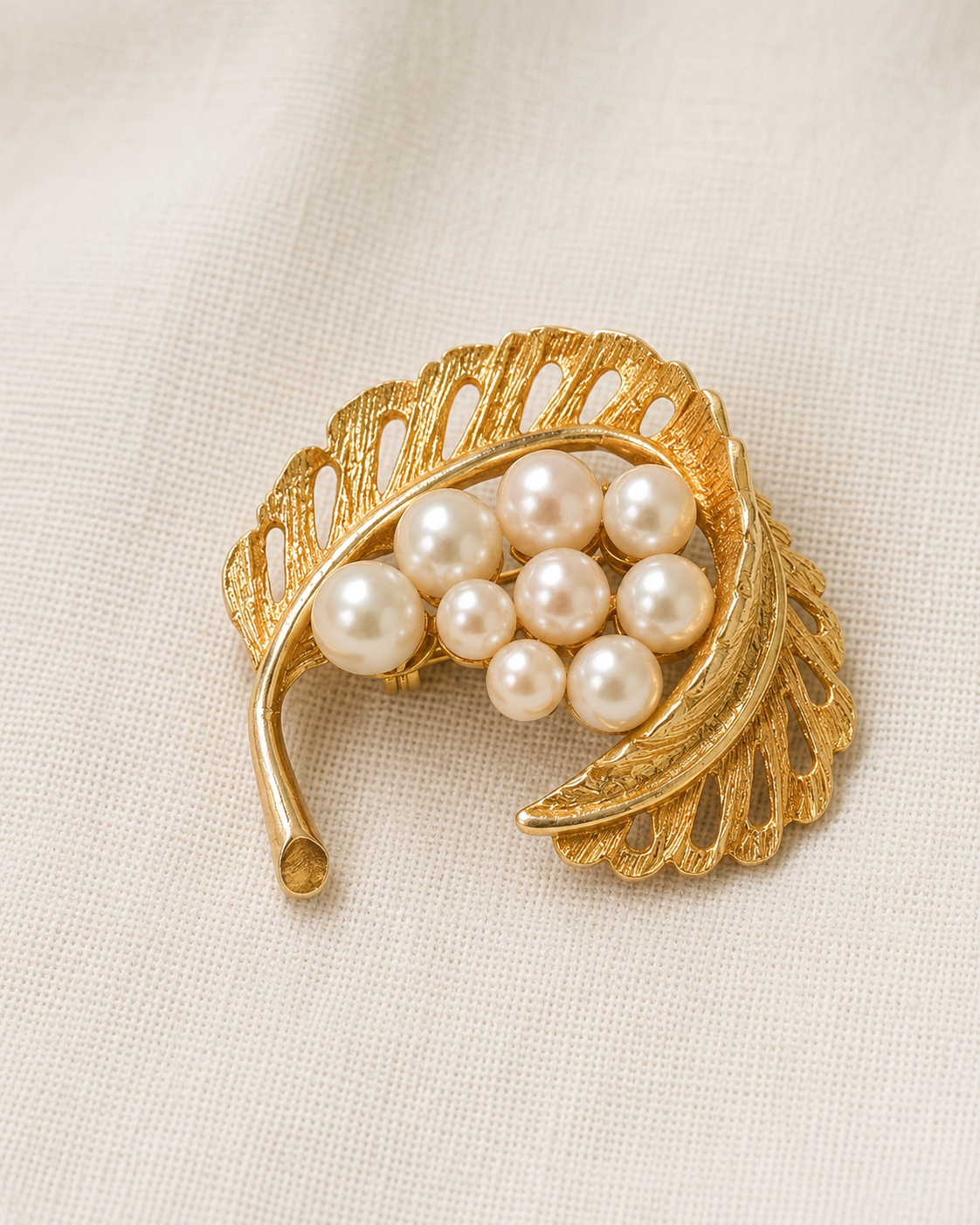 Gold-tone leaf faux pearl brooch on linen