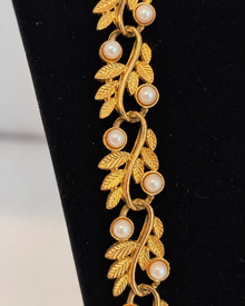 Close view of gold-tone leaf necklace with faux pearl accents