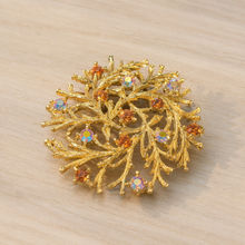 Gold-tone branch rhinestone brooch on wood table