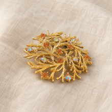 Gold-tone branch rhinestone brooch on linen