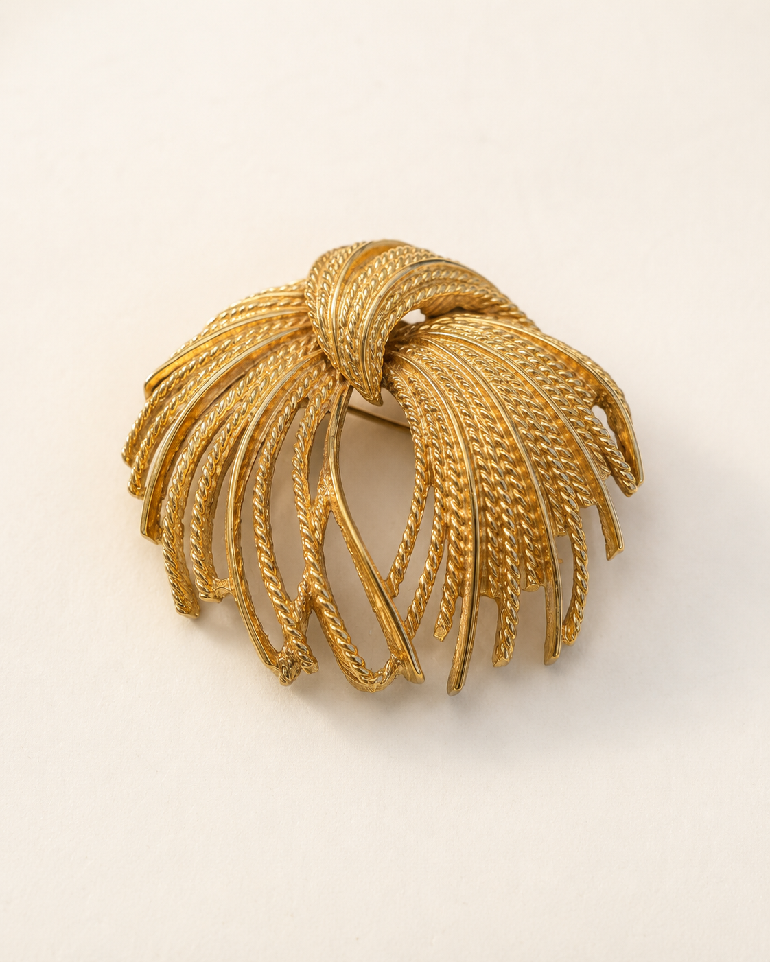 Gold-tone firework spray brooch on light background