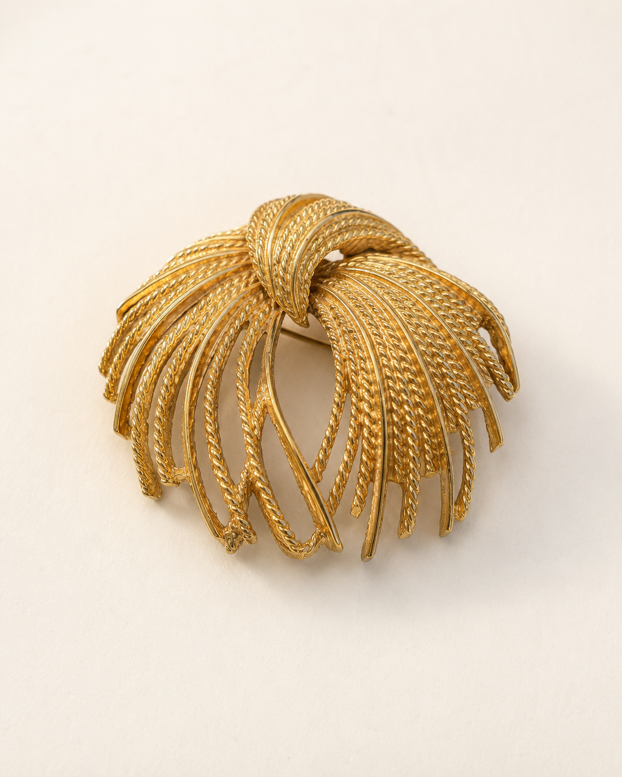 Gold-tone firework spray brooch on light background