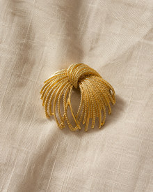 Gold-tone firework spray brooch on linen