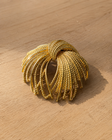Gold-tone firework spray brooch on wood table