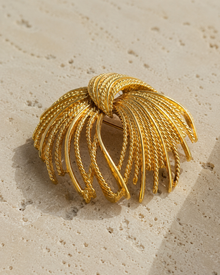 Close detail of gold-tone firework spray brooch on stone
