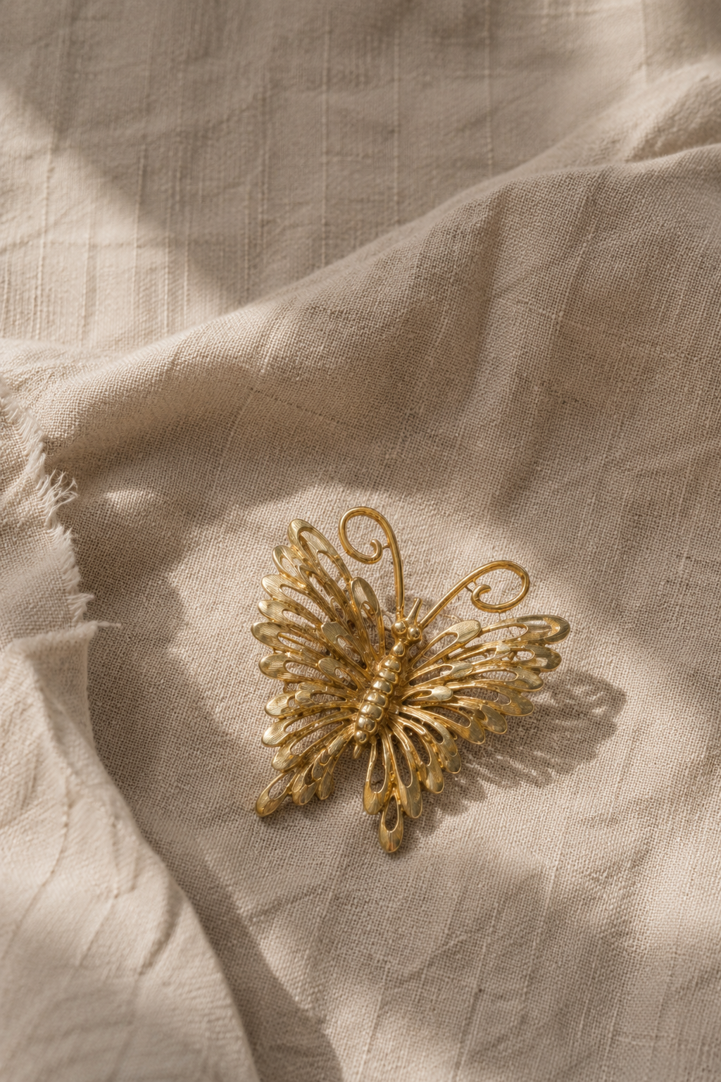 Gold-tone Monet butterfly brooch on linen