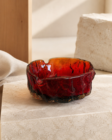 Amber red glass ashtray on a pale stone surface