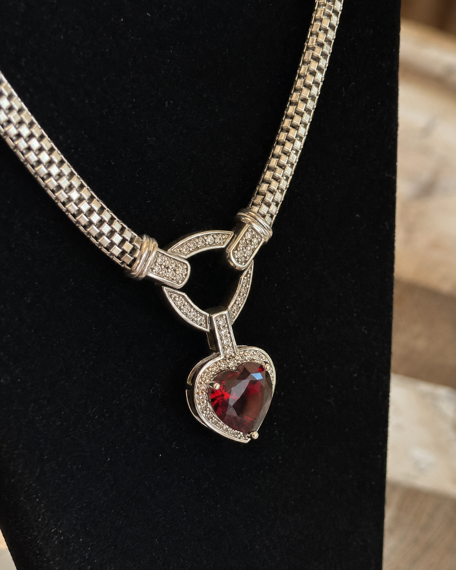 Close view of silver-tone red heart pendant necklace on black display bust