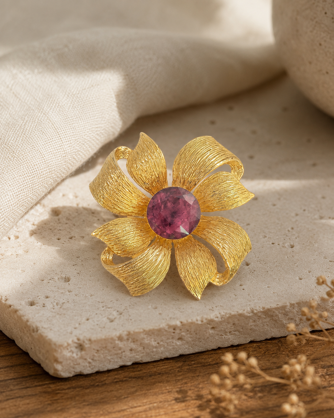 Gold-tone flower brooch with ruby-red center on pale stone