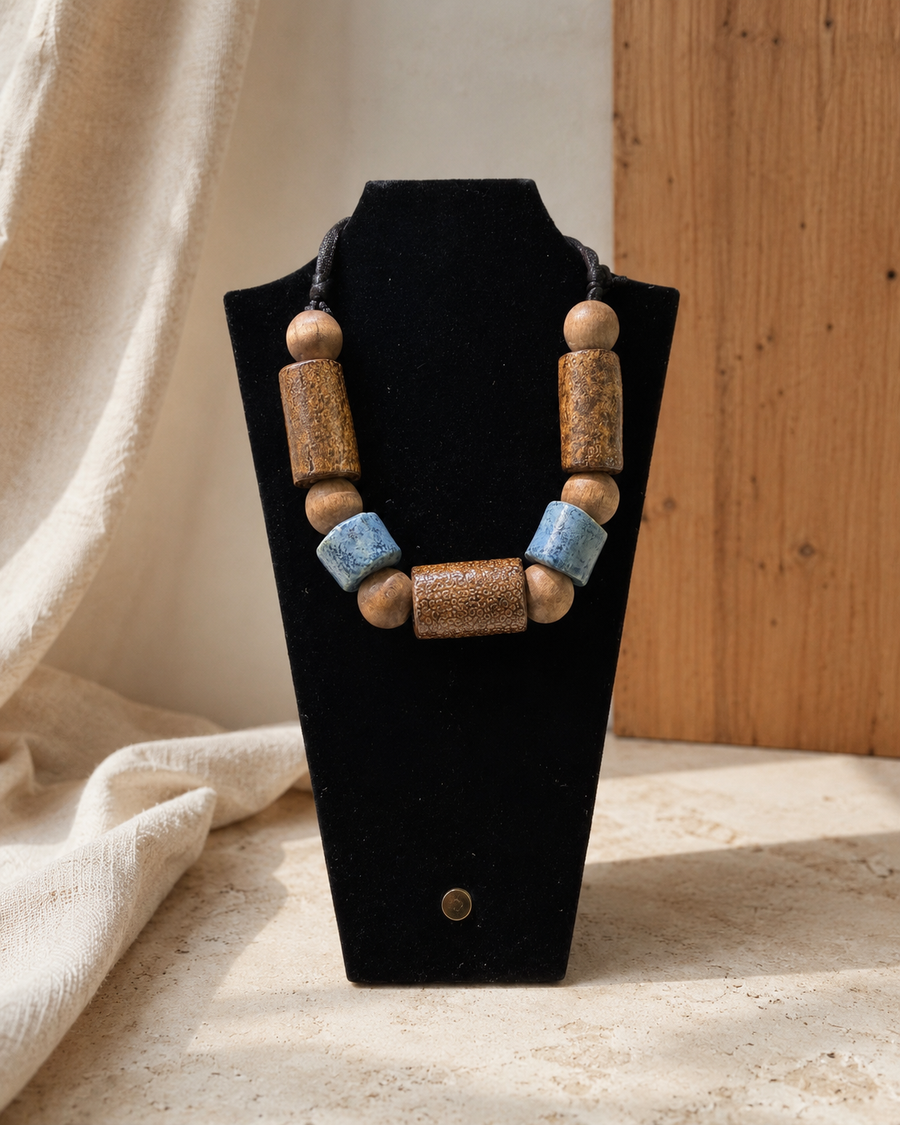 Wood and blue ceramic bead necklace displayed on a black bust