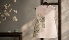 Pale pink kesi-inspired qipao hanging in soft natural light